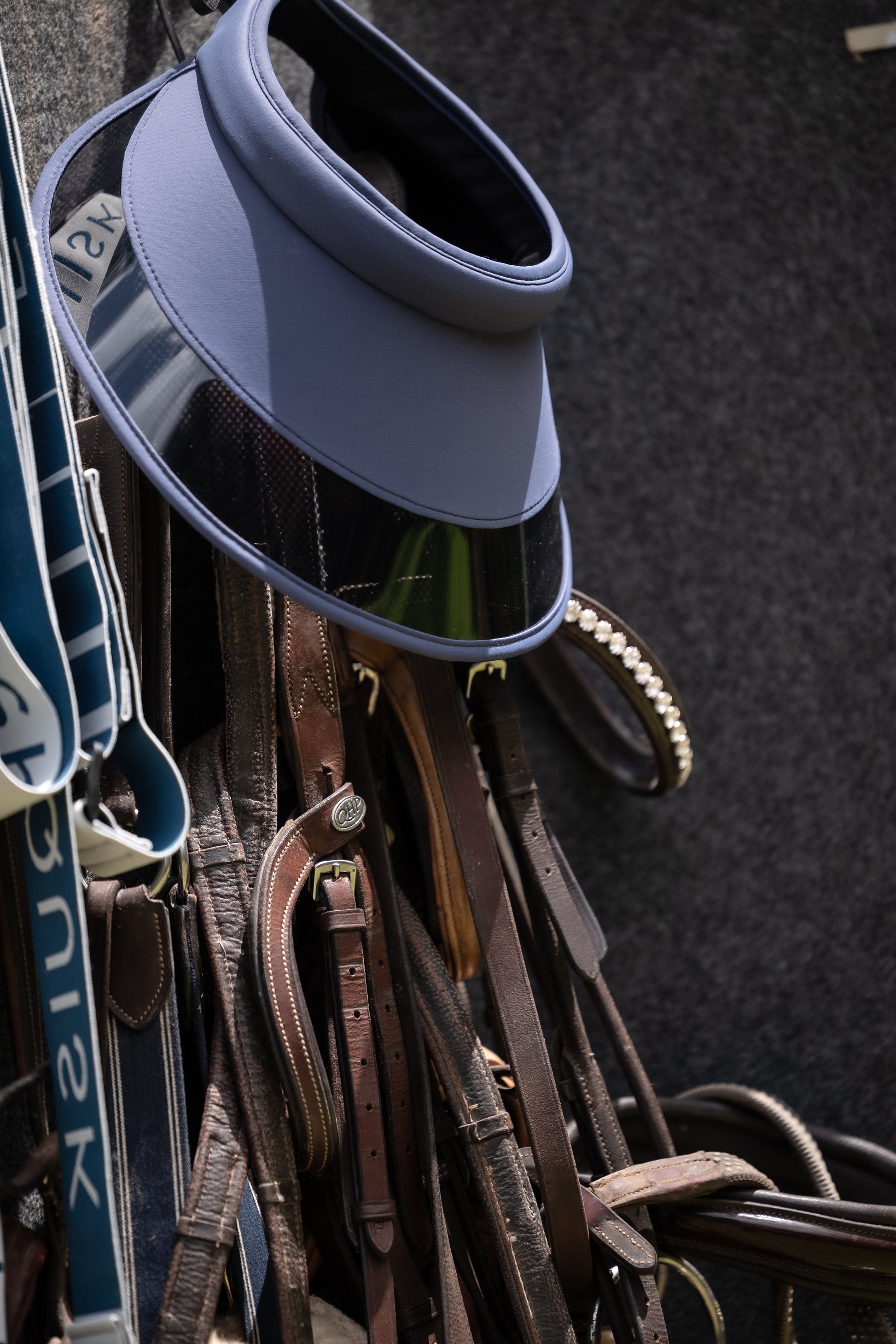 Blue visor on a rack with various leather straps and belts