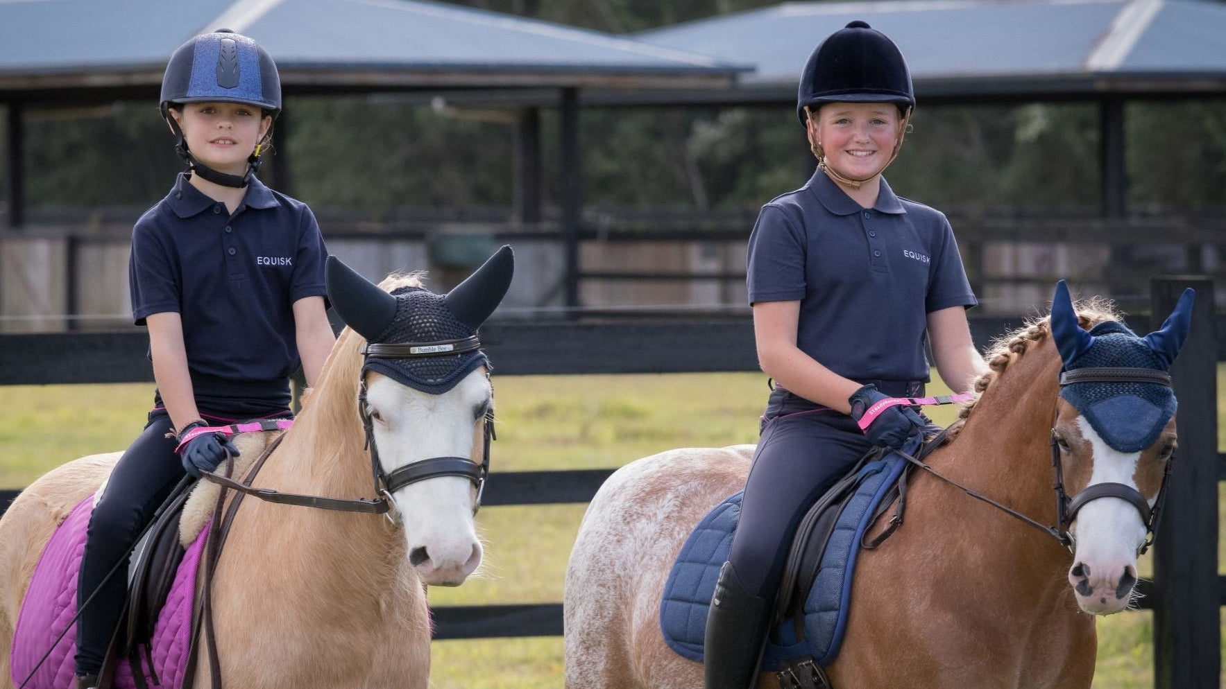 Two children riding horses in a stable area